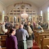 A view from the back of the church at what appears to be the end ofthe  mission_vespers service. Congregants are mostly standing now and are forming a line to the front of the church.