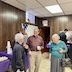 A photo of three people standing and talking in the church hall.