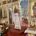 Father Aleksey standing in front of the Royal Doors blessing the congregation with a silver censor that he's holding in his right hand. His left hand holds a gold candelabra made up of three candles and a cross.