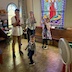 Four youths in the choir loft; three are pulling on thick ropes to ring the church bells, which are not visible. The same three are still pulling on the ropes to ring the bells, but now there's a young boy in the foreground, and he's looking at the camera.