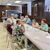 Photo a table, in the church, that runs from the bottom right of frame to the center of the photo. Several people are seated on both side of the table and are eating.