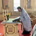 Side view of Fr. Aleksey placing the cloth icon on top of the table at the front center of the church. This is the same table described earlier, but the platter of bread is no longer on the table.