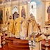 Four clergy members are standing in front of the Royal Doors. Two are holding the Royals and one is holding a cross. The photo is not clearing showing what, if anything, the fourth clergy member is holding. This photo was taken from the right side of the church, to the left of the clergy.