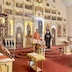 Fr. Aleksey and Archbishop Mark are stand before the iconostas and looking at each other. The view is a wide shot from the left side of the church, near the front.