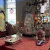 Photo of the altar table similar to the one shown earlier, but this photo was taken during the day, and light is streaming through the stained glass windows. The red cloth on the table now shows more detail, and the archbishop's mitre is on the table near the cross on the right. Archbishop Mark is shown on the left-side of the frame at a table, preparing holy communion.