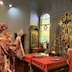 Archbishop Mark is shown standing before the altar table with his hands raised in prayer. He appears on the left side of the frame, and Fr. Aleksey is standing, facing him, on the right side of the frame.