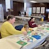 Two woman, a man, and a young boy are seated at a long table and making Christmas cards.